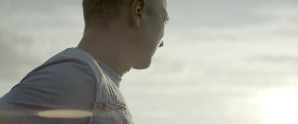 A man looks over at the setting sun on a cloudy day