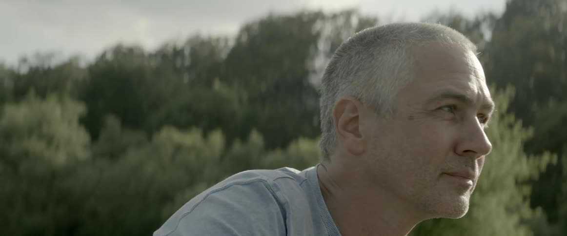 A gray haired man stares and looks around on a sunny day