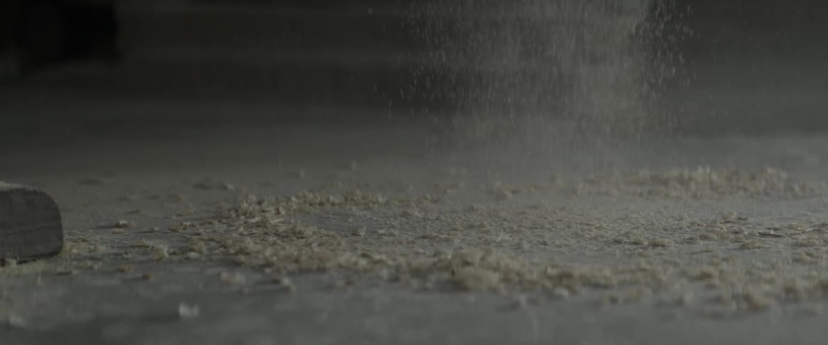 Sawdust falls slowly on the concrete ground