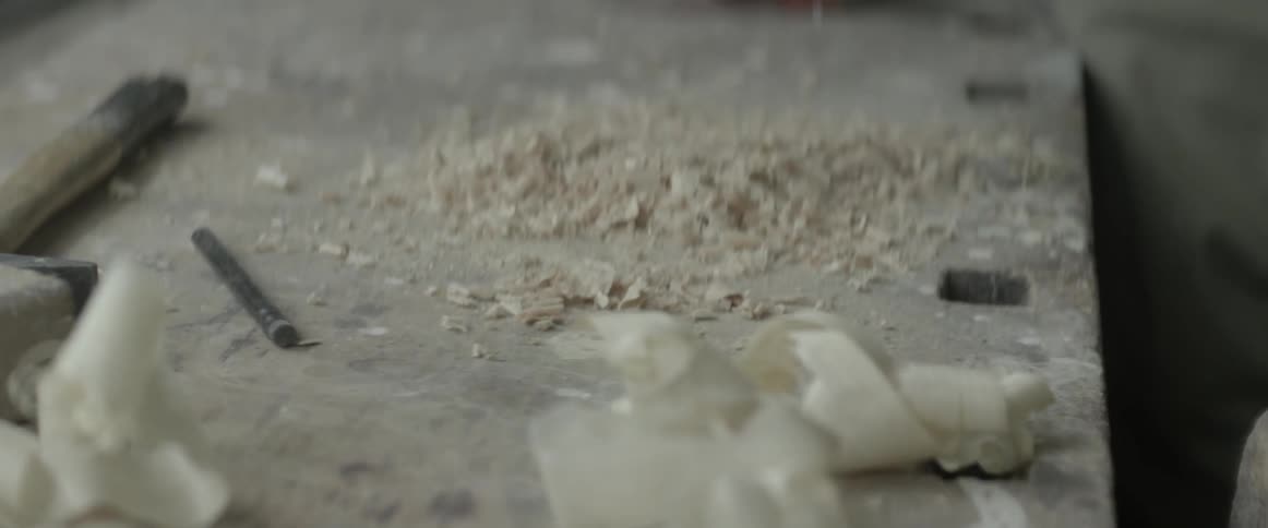A person brushes sawdust off their hands