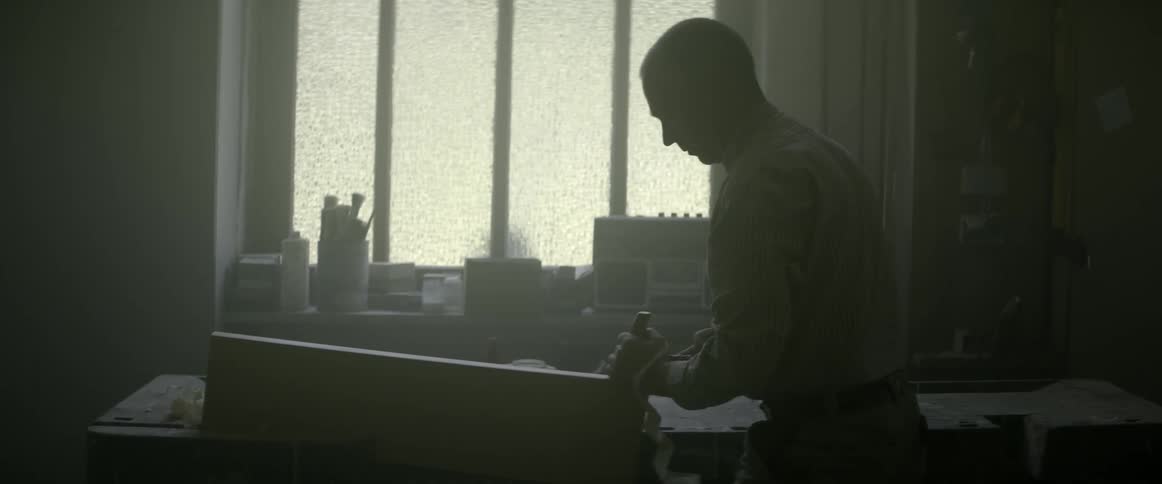 A man shaves a wood block in a workshop