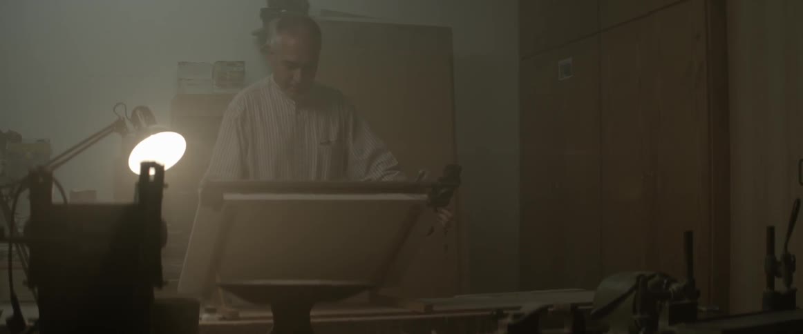 A man in a white shirt adjusts a board under a light