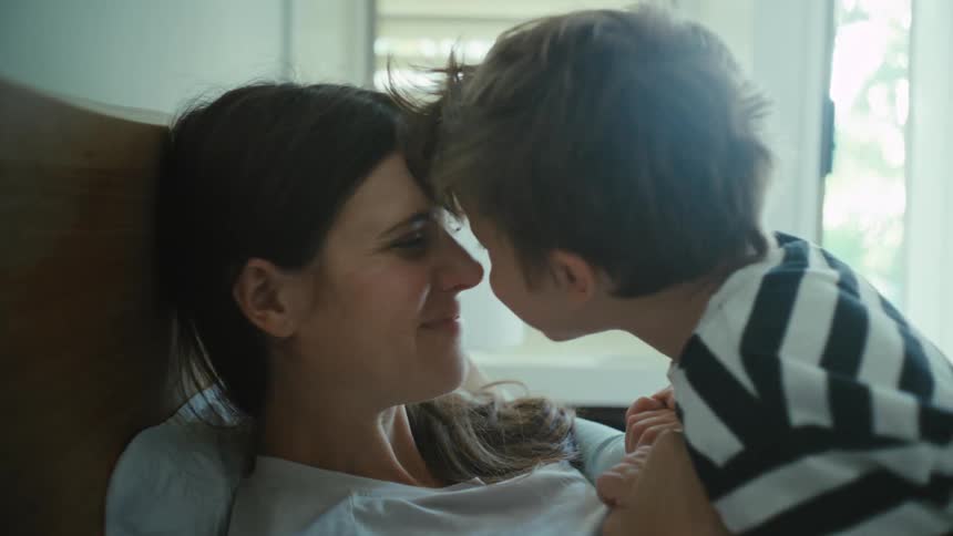 Mother and son rubbing noses in the bedroom