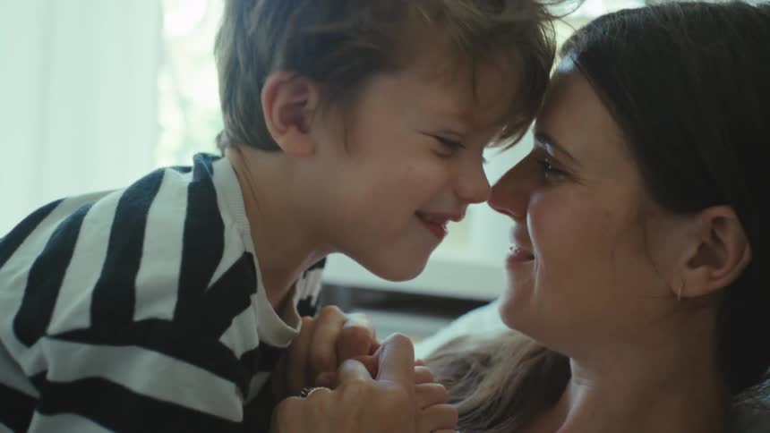 Mother and son kissing with an eskimo on the sofa at home