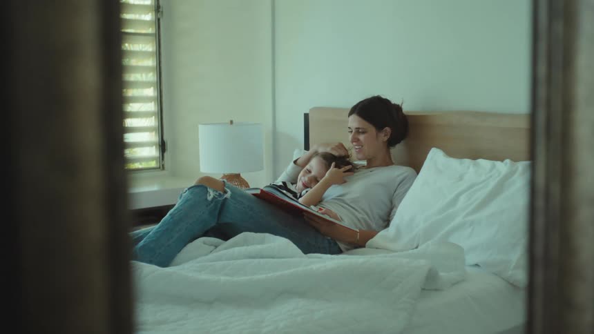A mother reading to her son on the bed