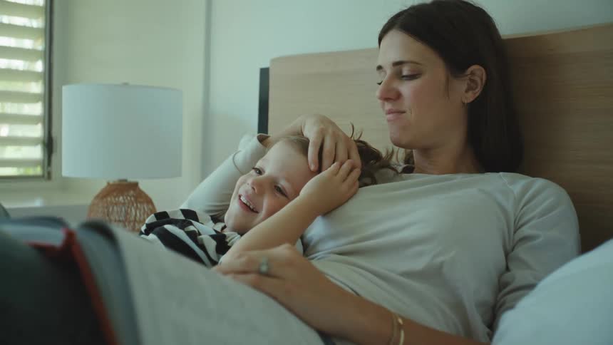 Mother and son lying in bed while hugging each other