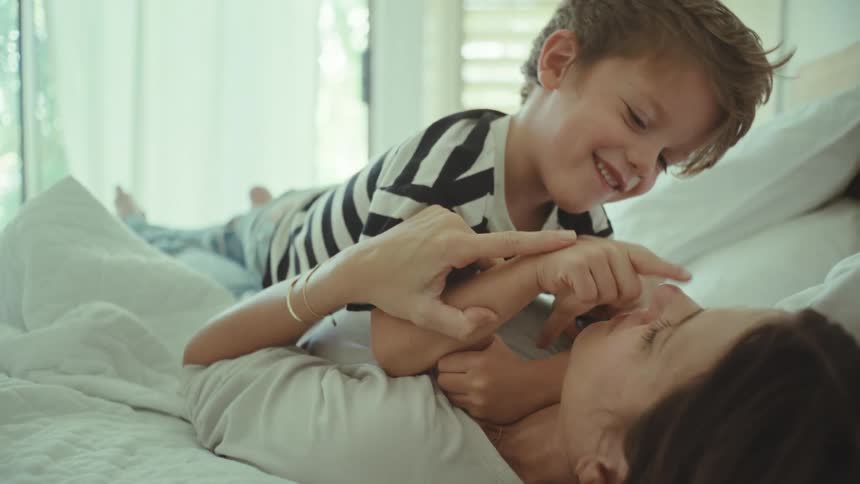 Mother and son playfully touching each others noses in the bedroom