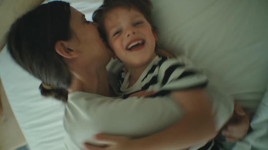 Mother and son playfully playing in the bedroom