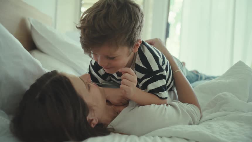 Mother and son resting in bed kiss each other