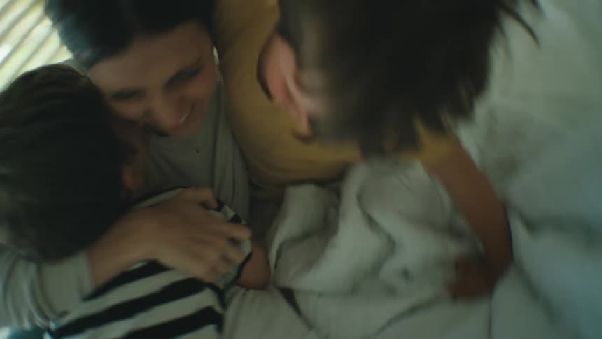 Mother playing with her children in the bed