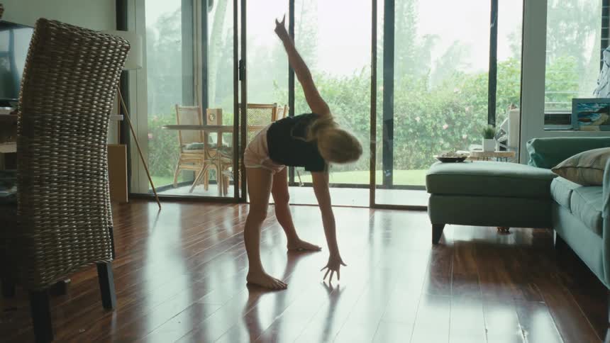 Girl doing calisthenics stretches on the living room at daytime