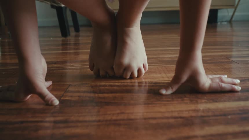 A girl trying to balance herself with her hands on the floor