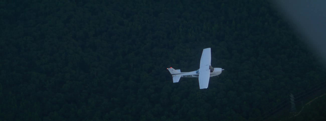 Small airplane flying over a forest seen from another plane
