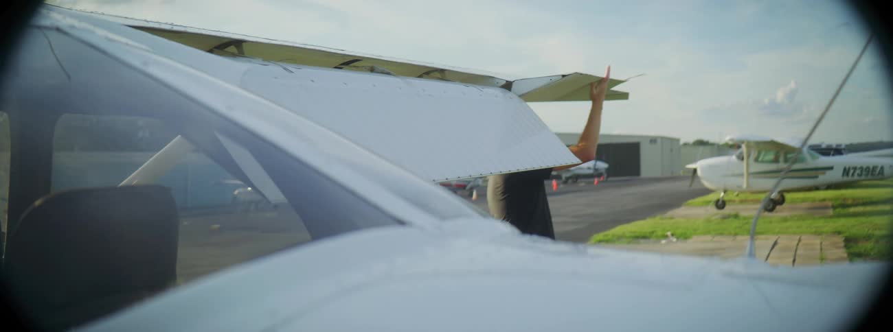 A man wearing sunglasses inspecting an airplane near tarmac