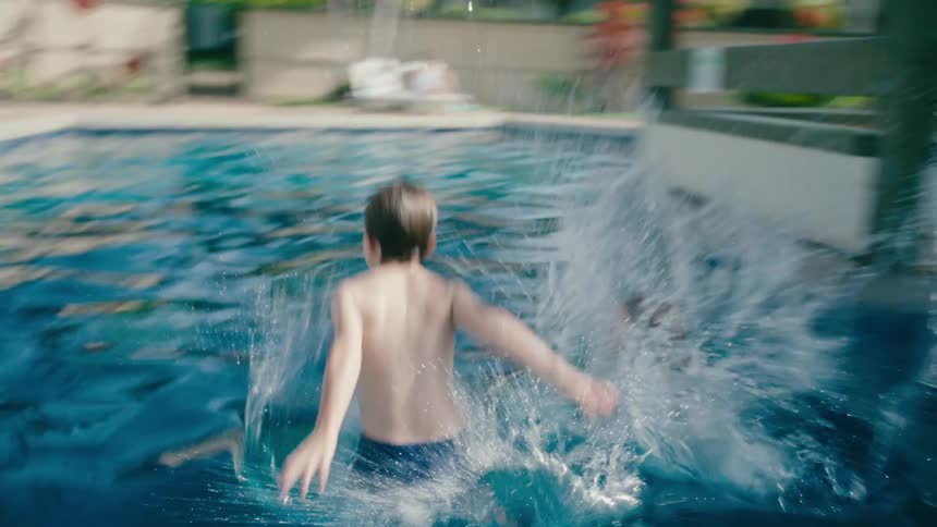 Siblings racing each other jump on the pool