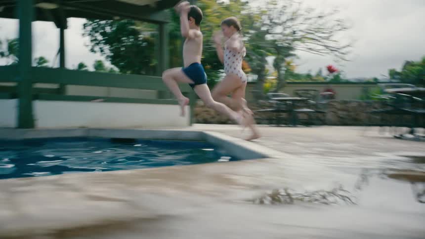 Brother and Sister running to jump into the pool