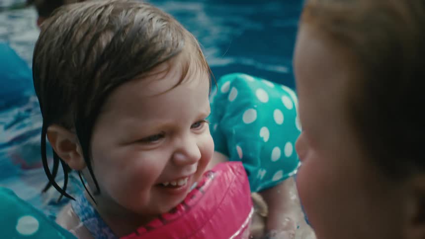 Male and female toddler playing with an older female child on a pool outdoors during day time