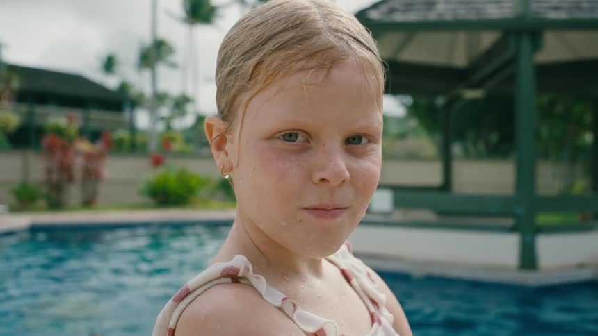 Close up of the face of a girl in a swimsuit next to the swimming pool