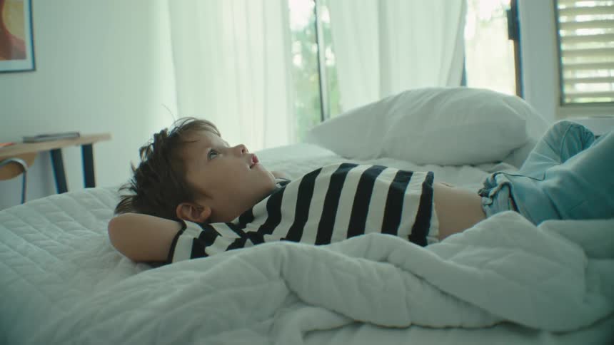 Boy relax laying in bed in the bedroom