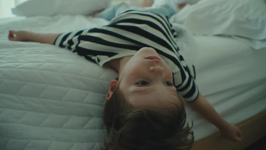 A small child sprawled out on a bed