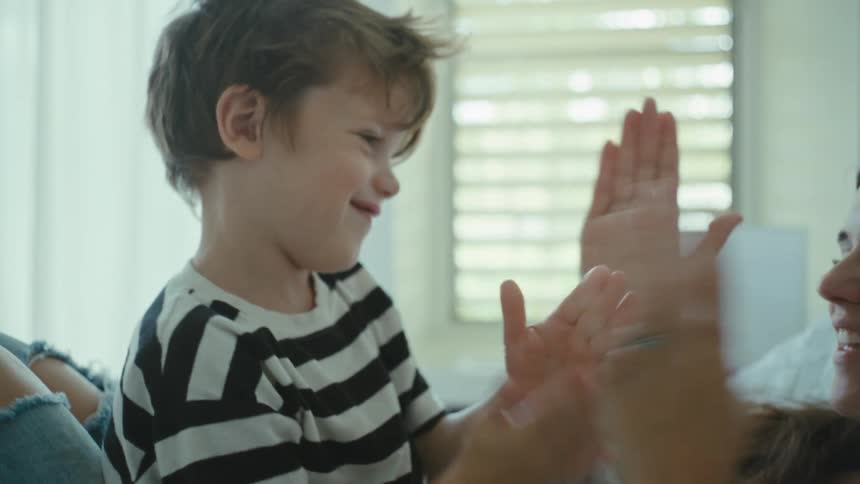 Mother and son play hand clapping games in the bedroom