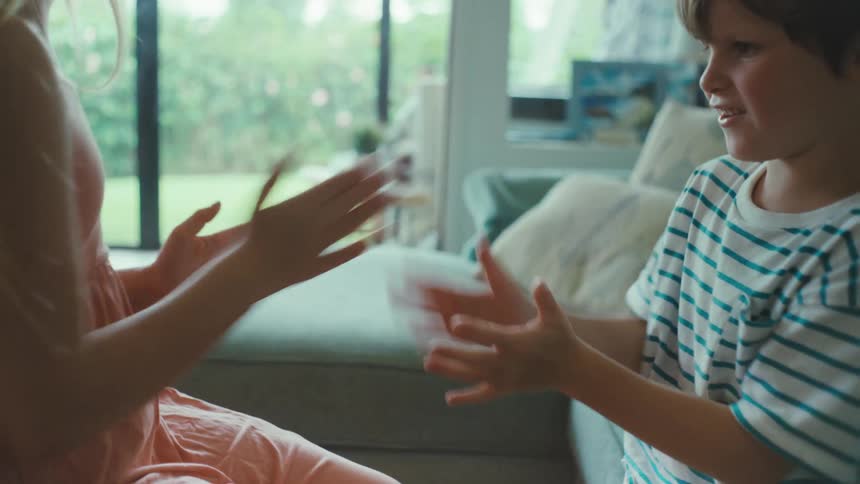Two children playing patty cake in a living room