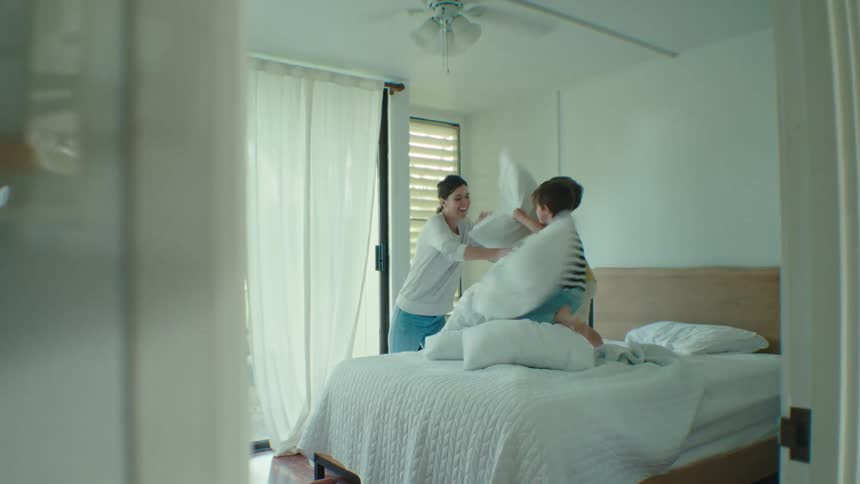 Mother having a pillow fight with her children in the bedroom