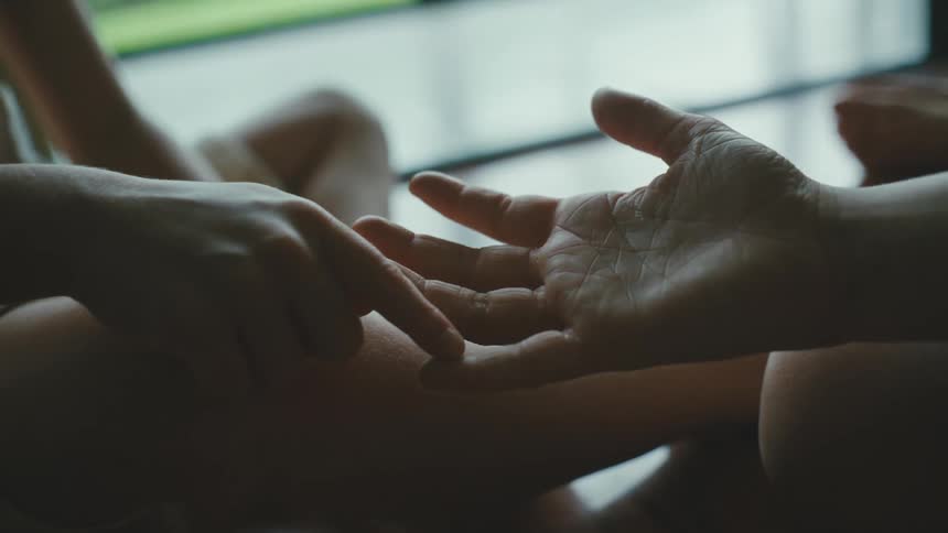 boy playing with someones hand and fingers indoors during day time