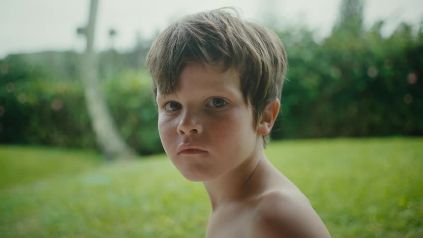 A small boy with no shirt on looking sad