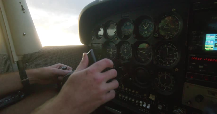 Male pilot steering a plane and operating the dashboard during day time