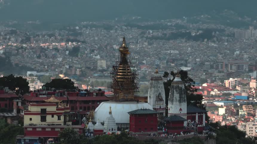 An aerial view of a tower at the top of a mountain next to a city