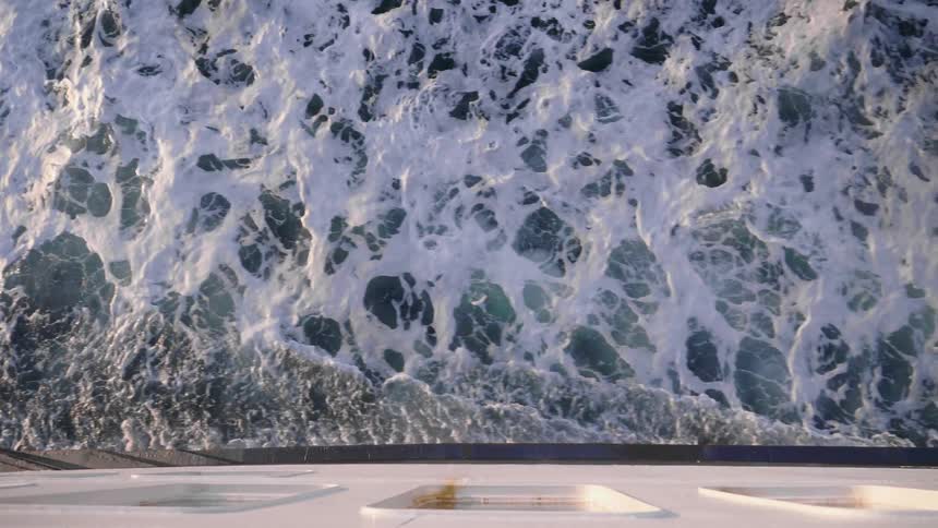Waves and foam on the wake of a ferry moving on the sea