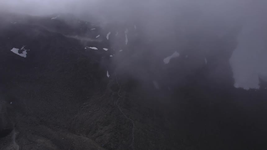 An aerial view of a mountain range with snow falling down