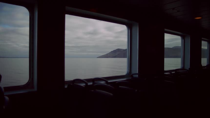 Serene scene of a lake with mountains in the distance seen from a ferry