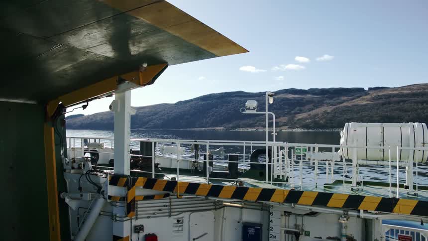 The deck of a ferry on a lake next to the mountains