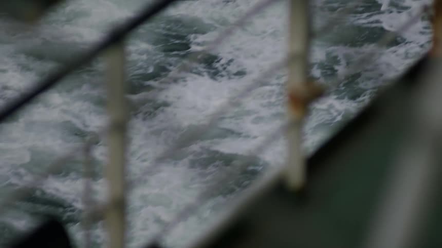 A large ship travels atop the ocean leaving foamy wake behind it