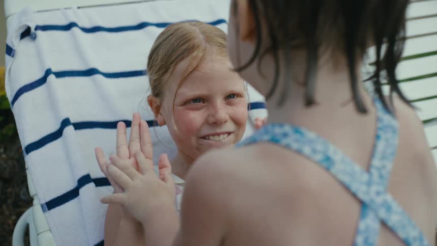 Sisters playing hand clapping games next to the swimming pool