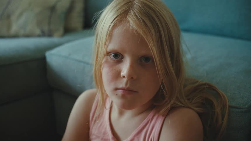 Girl sitting on the floor of the living room looking at the camera