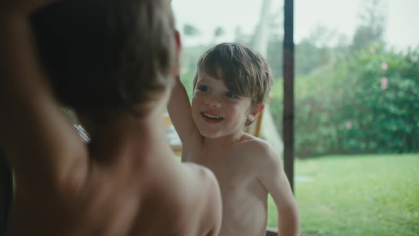 Two children are looking out a large window or glass door playing with each other
