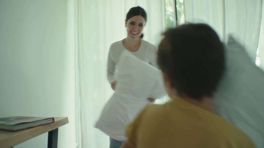 Mother and son pillow fighting in the bedroom