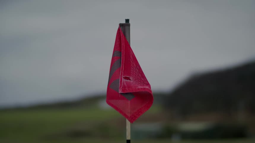 Close up of a red flag waving in the wind on a golf course