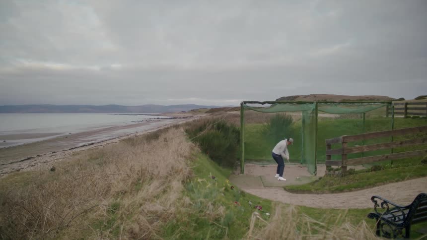 A man drives the golf ball into the net