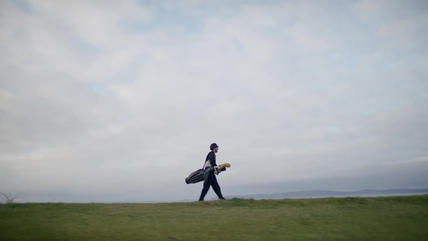 A man is carrying his golf bag on the course