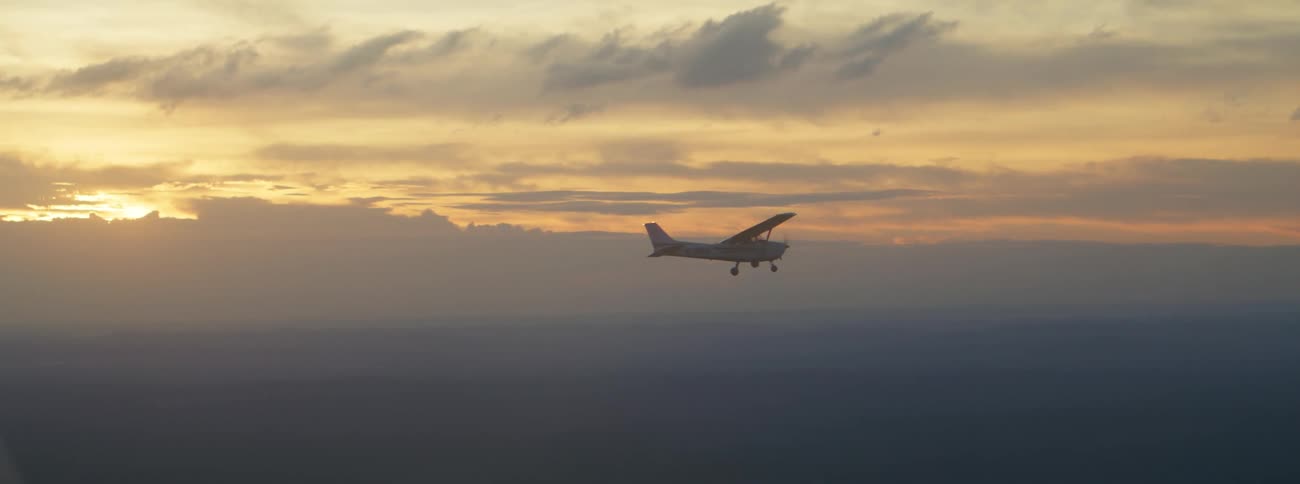A plane flying outdoors with the sunset in the distance