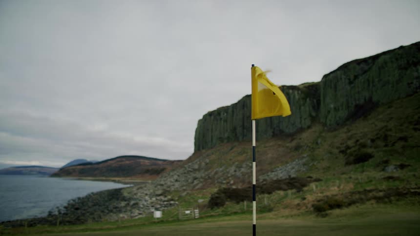 A flag waving against the wind on a beach golf course