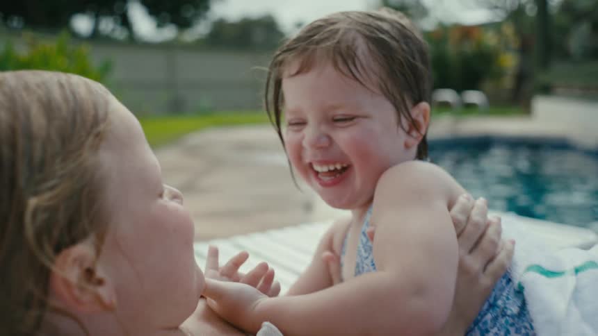 Sisters smile and laugh next to the swimming pool
