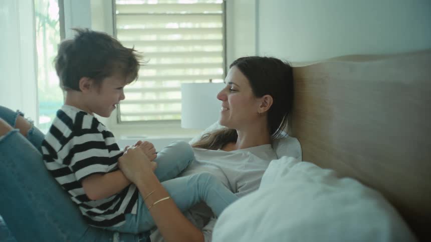 A mother and person plying and kissing on the bed
