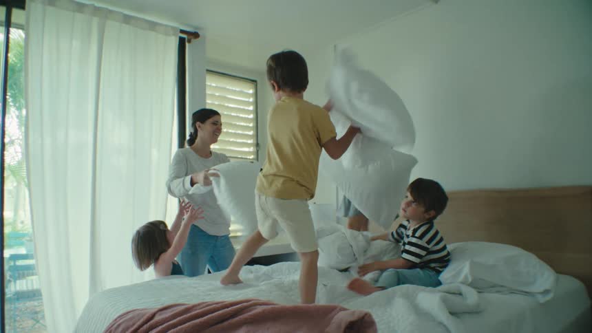 Family playing a pillow fight in the bedroom