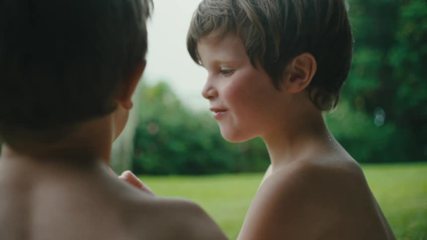 Two children talking while licking ice cream outdoor at midday