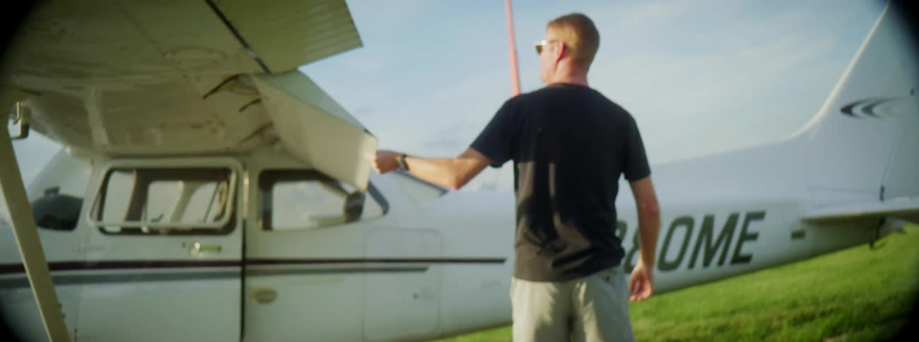 A man walking around doing a preflight check on a plane